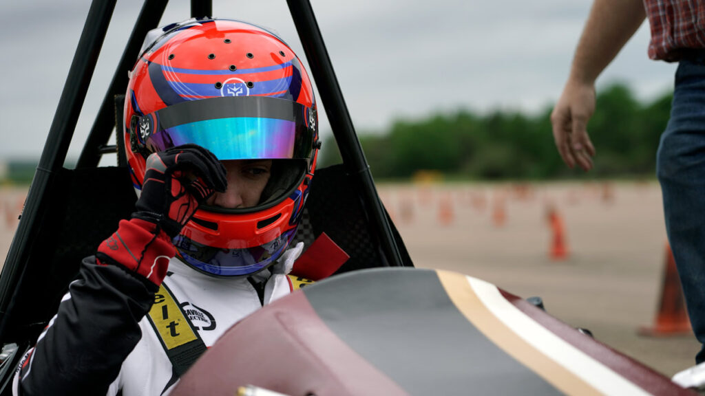 A race car driver lowers his visor.