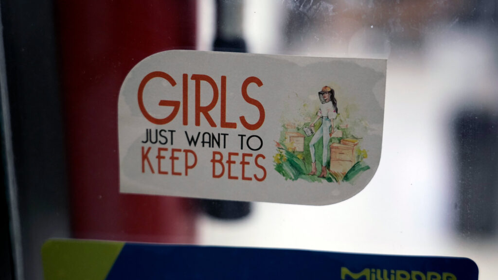 A sticker on a window that says Girls Just Want to Keep Bees.