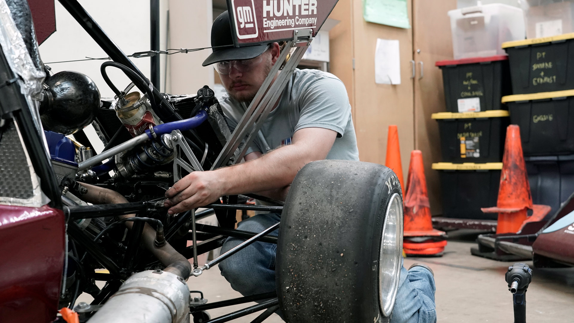 An automotive engineer takes a wheel off their race car.