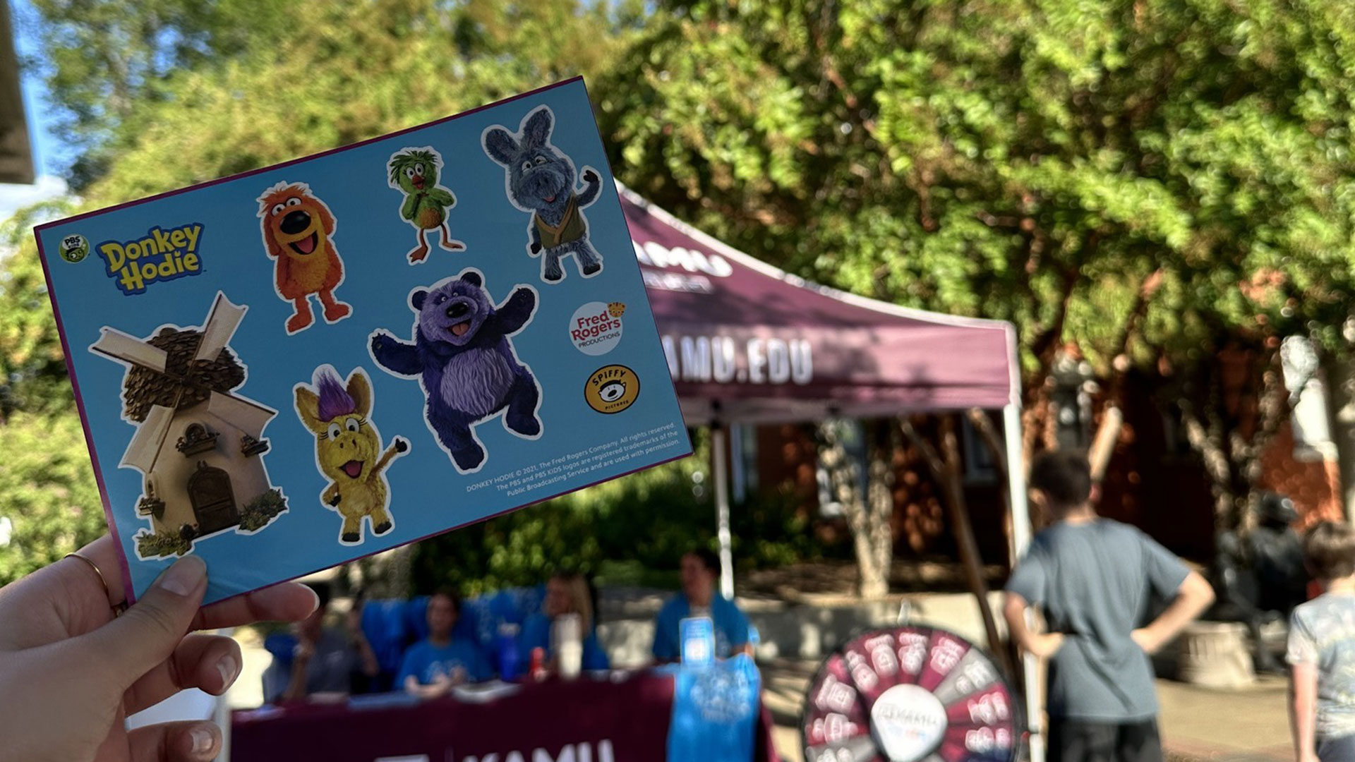 A Donkey Hodie sticker sheet in front of the KAMU tent