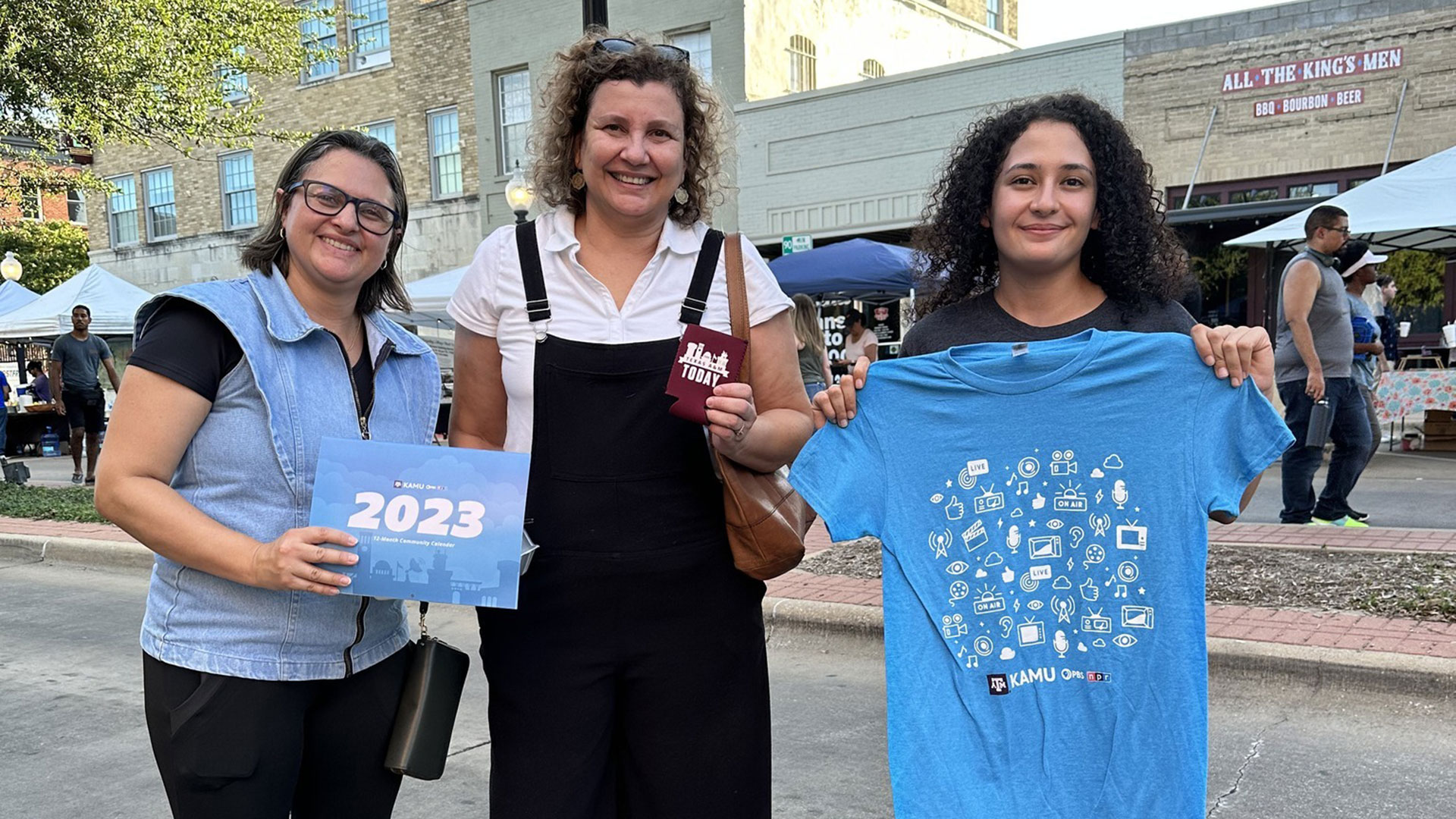 People smile and pose with their KAMU merch