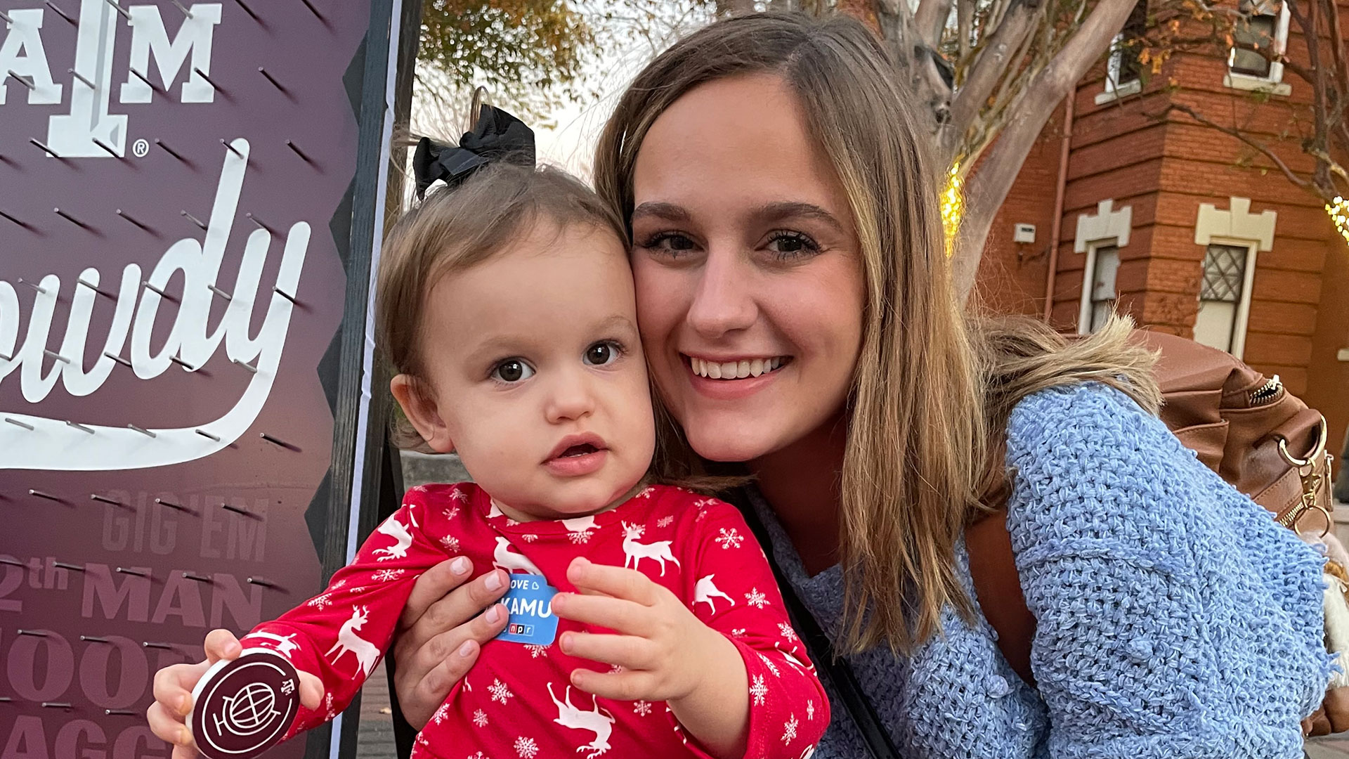 A mother poses with her young daughter next to the KAMU plinko board