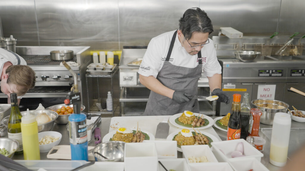 Chef Ray places fried eggs on top of his finished dish.